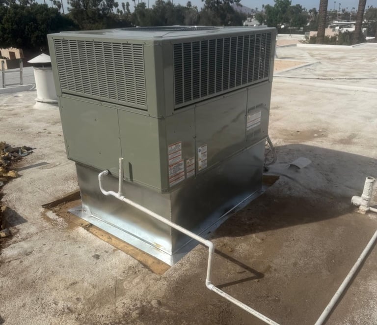 Large beige commercial HVAC rooftop unit mounted on concrete pad with metal framework in outdoor industrial area