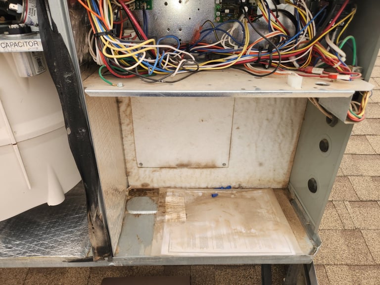 Open metal cabinet with tangled wires and cables on top shelf, empty compartment below