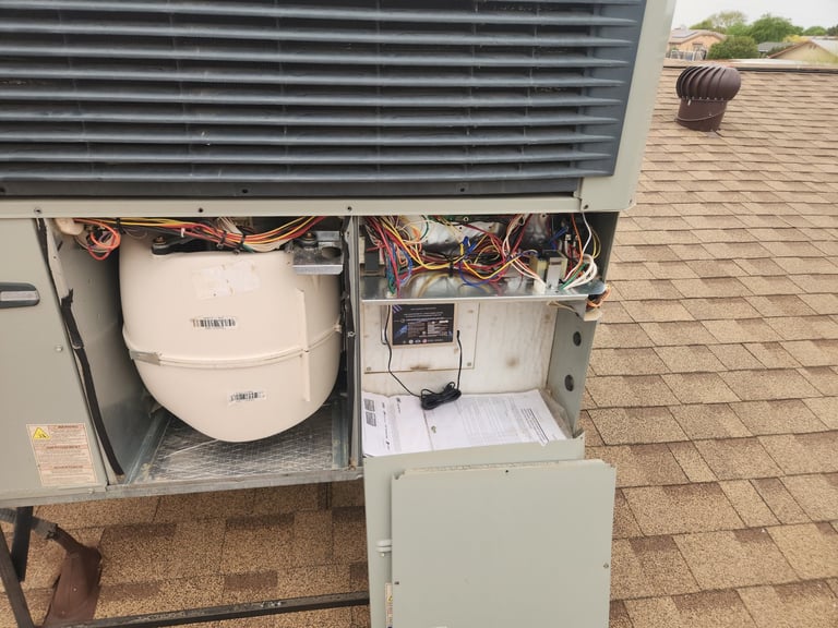 Open HVAC unit on roof showing exposed mechanical components, wiring, and round tank with copper tubing visible