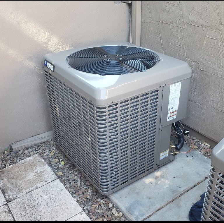 Outdoor air conditioning unit mounted on concrete pad against white brick wall